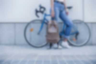 kobieta stojąca na tle roweru z plecakiem
