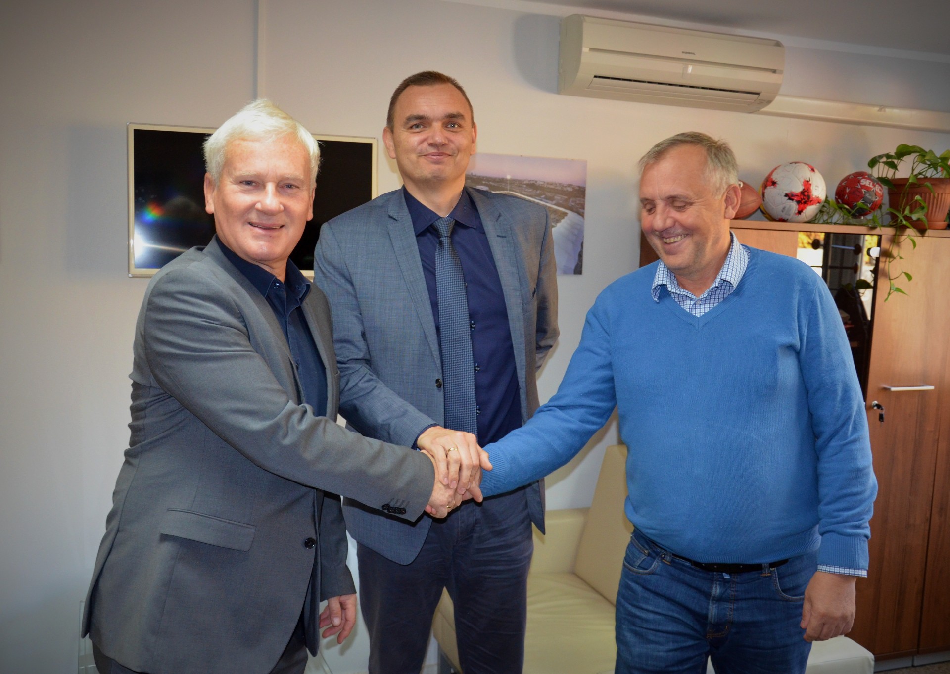 trzech mężczyzn ściskających dłonie na znak uzgodnionej współpracy