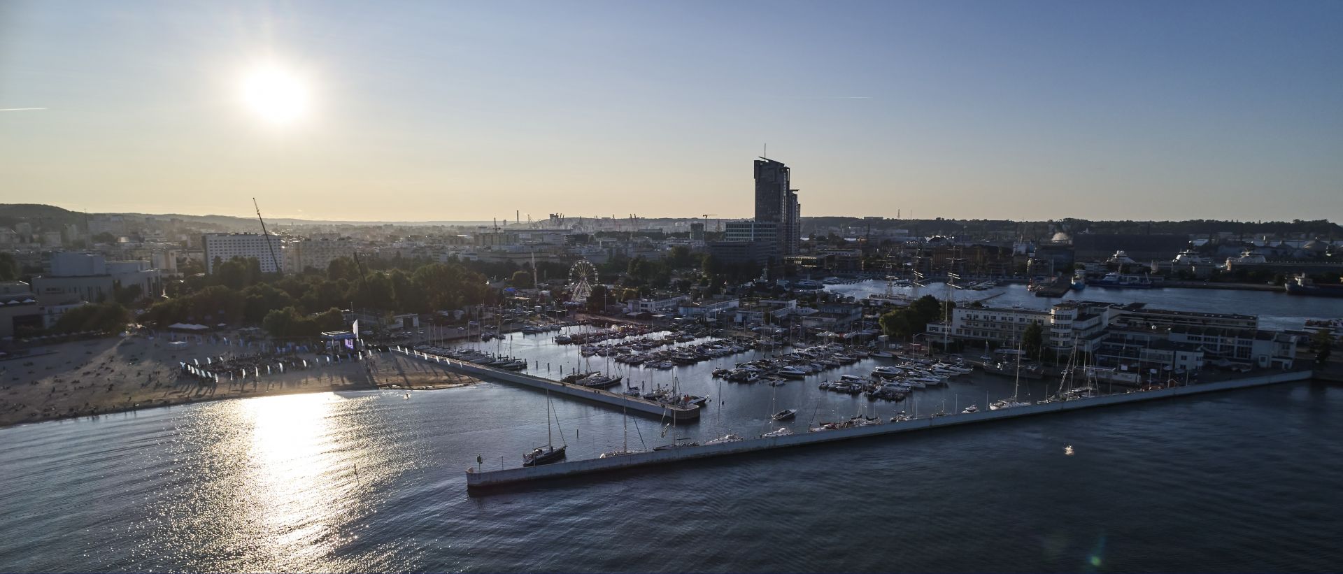 widok na marinę Gdynia z lotu ptaka, w tle słońce i Sea Towers 