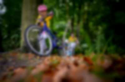 Dziewczynka pchająca rower w lesie