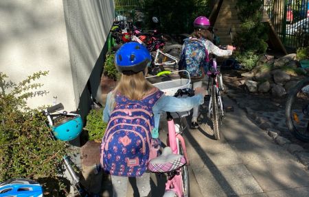 dziewczynka z plecakiem prowadząca rower