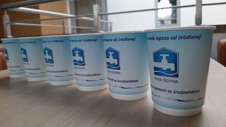 Kubki z wodą z logiem PEWIK stojące obok siebie w rzędzie