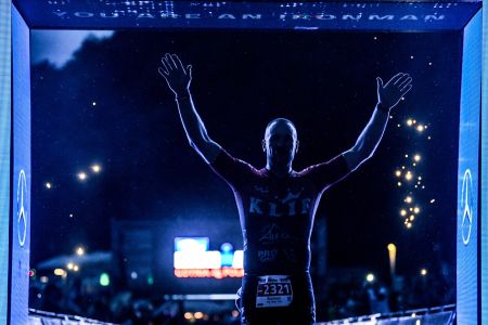 zawodnik podnoszący ręce w geście triumfu na mecie - zdjęcie w nocy