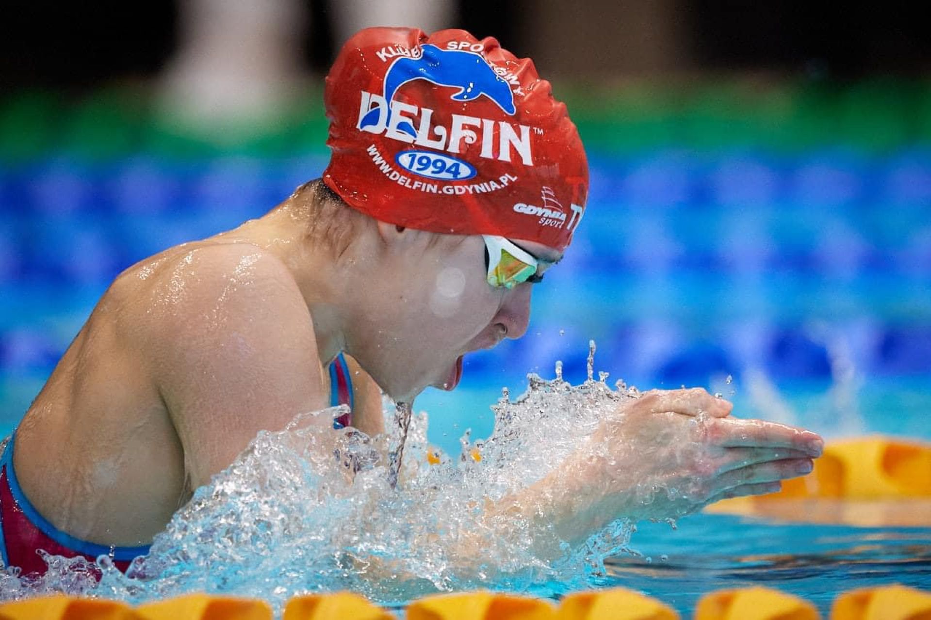 Zofia Chrzan w wodzie podczas pływanie w czepku z logo klubu Delfin Gdynia 