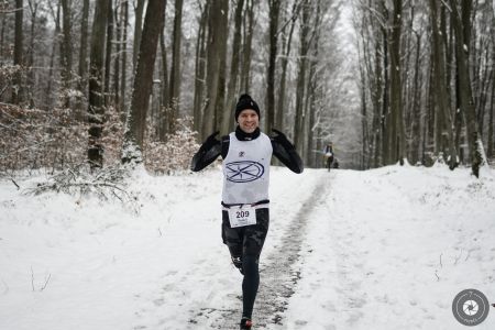 Zawodnik pokonujący trasę leśnego półmaratonu w zimowej scenerii