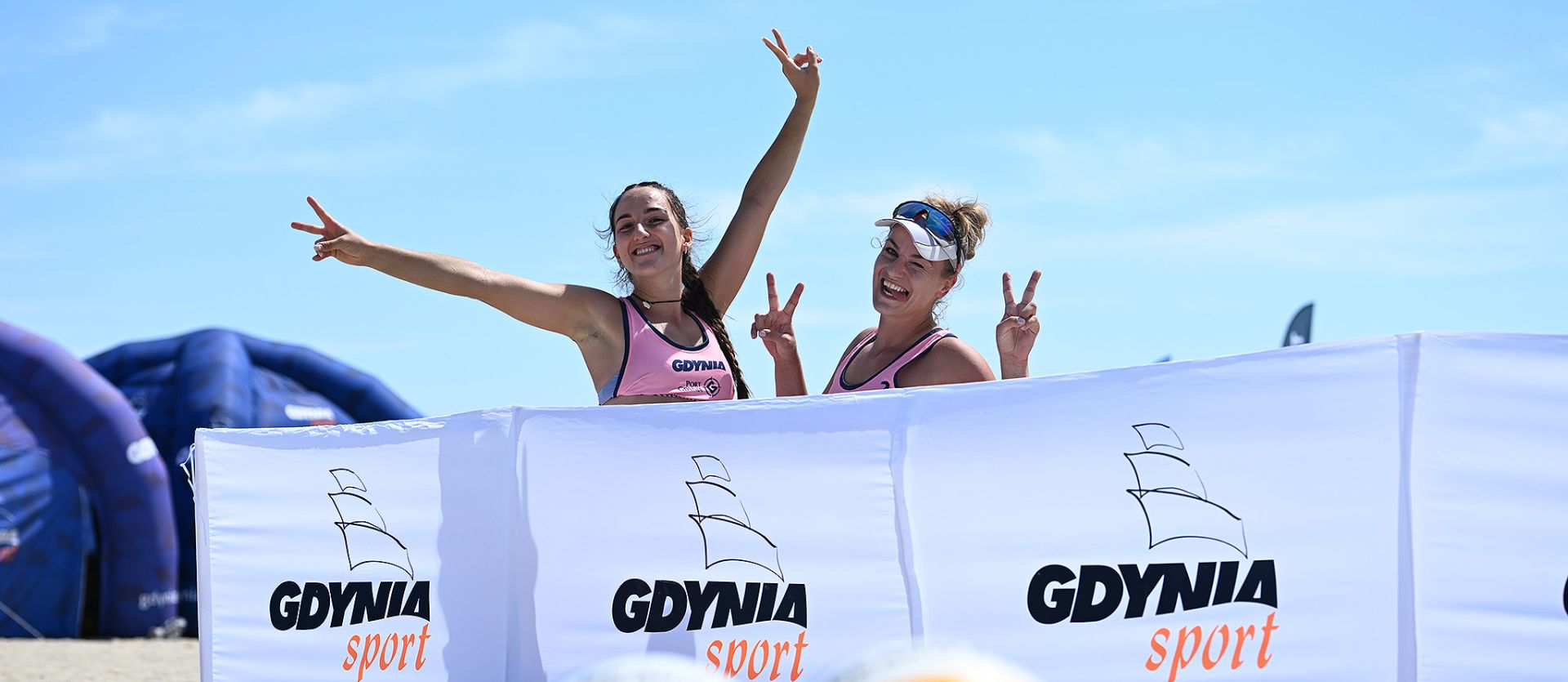 siatkarki plażowe za parawanem wykonujące wesołe gesty