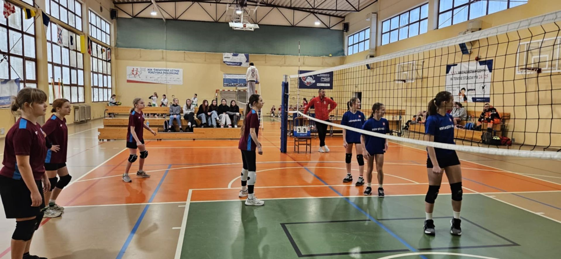 dzieci grające w siatkówkę w hali sportowej